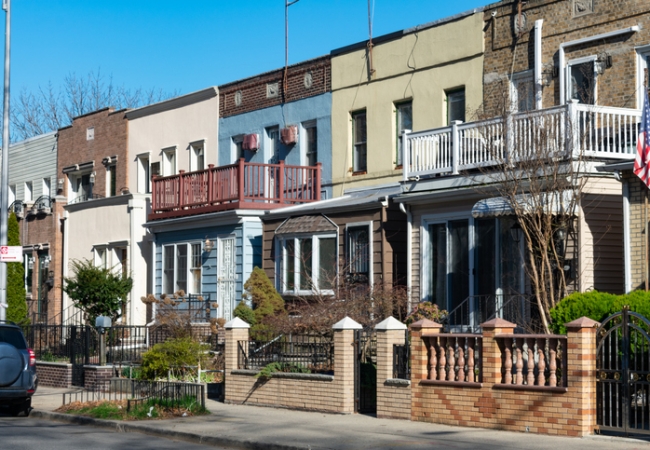 A row of beautiful and colorful old brick homes along the sidewalk in Astoria Queens New York