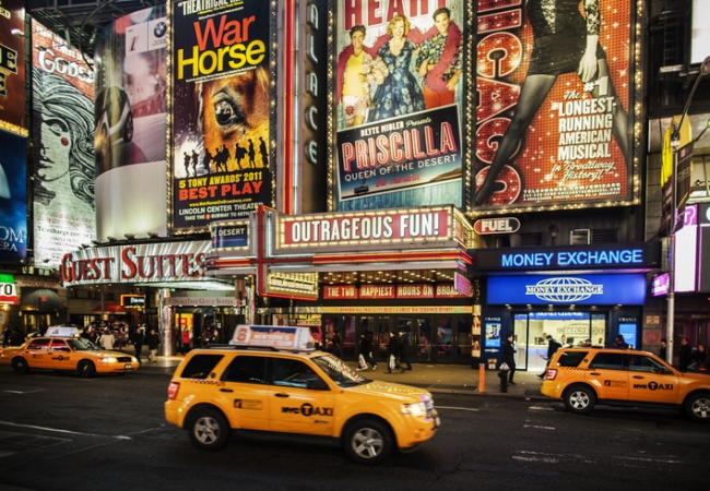 Bright lights and bustling crowds in Times Square, showcasing NYC's vibrant entertainment scene with theaters, billboards, and live performances.