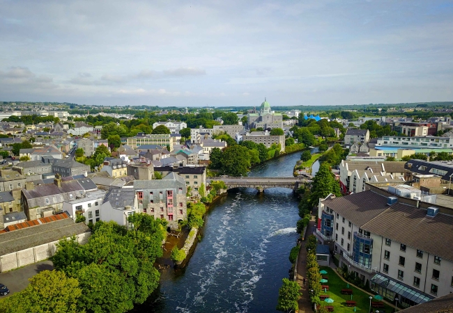 A picturesque view of Galway’s waterfront with charming houses and a coastal backdrop.